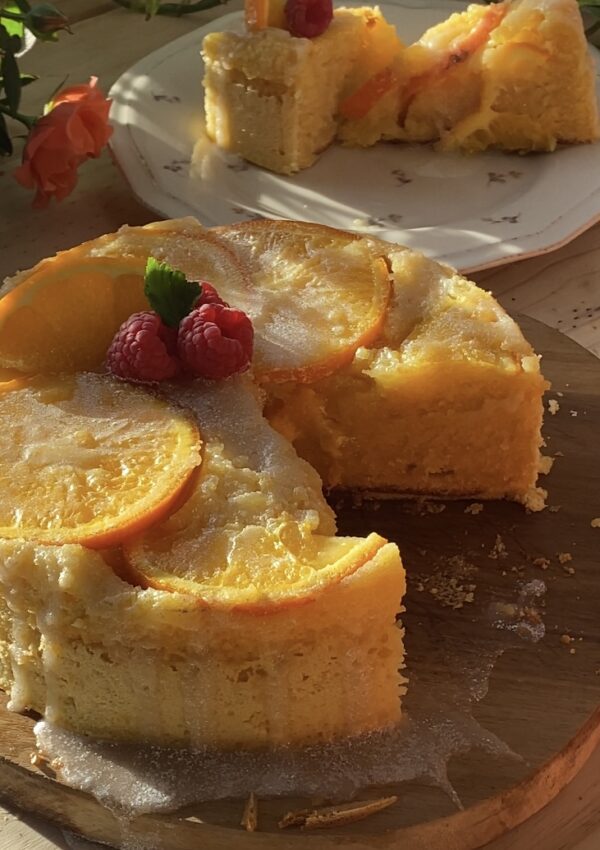 A beautifully moist upside-down orange cake with vibrant caramelized orange slices on top, displayed on a rustic wooden board, showcasing its golden, fluffy texture.