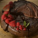 A perfectly baked chocolate cake, with a moist, fluffy texture and rich, indulgent chocolate flavor, topped with smooth chocolate frosting and some fruits