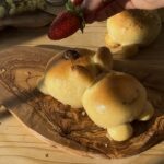 Adding fresh strawberries to decorate the freshly baked bunny bread with chocolate, enhancing its presentation and flavor