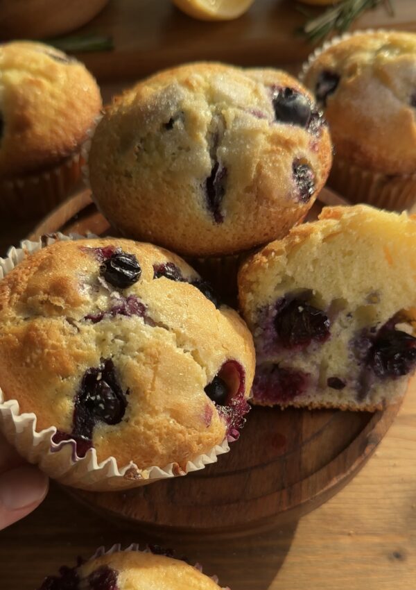 Freshly baked bakery-style blueberry lemon muffins, golden brown with bursting blueberries and a hint of zesty lemon, perfect for a delightful treat