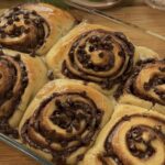 Golden-brown Nutella rolls fresh out of the pan, showcasing a gooey chocolate center and topped with melting chocolate chips for a delicious, indulgent treat.
