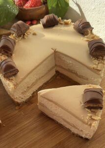 A no-bake Kinder Bueno cheesecake with a creamy texture, showcasing a slice cut and placed in front of the whole cake.